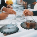 Close-up of hands tracing a technical drawing for mechanical gear designs
