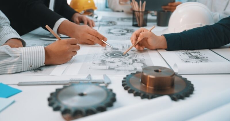 Close-up of hands tracing a technical drawing for mechanical gear designs