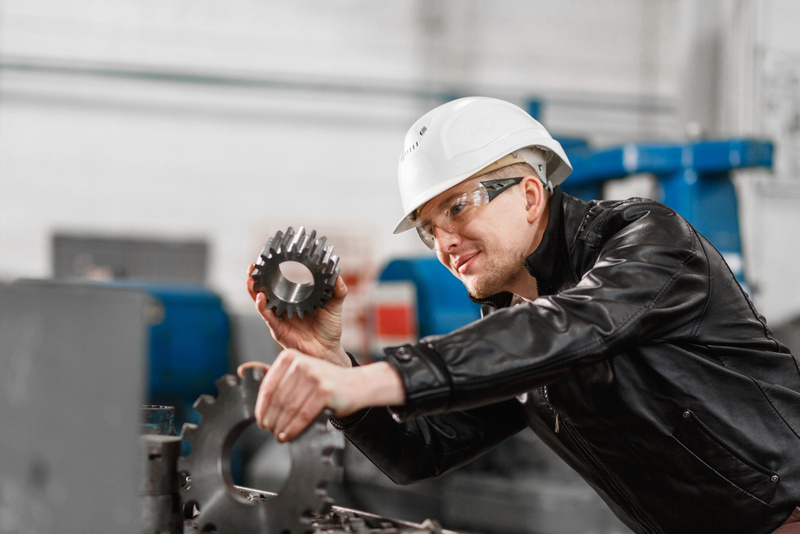Technician in eye protection compares two gears of different sizes